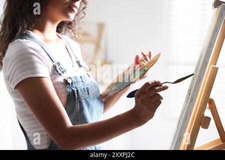 Frau, die ein Bild mit einem Palettenmesser im Atelier zeichnet, Großaufnahme Stockfoto