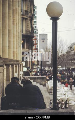 Zwei Obdachlose sitzen neben Flaschen Bier aus der Dinkelacker-Brauerei vor dem Königsbau am Schlossplatz, hinter der Königstraße und Stockfoto