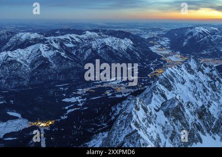 Tagesanbruch auf dem Gipfel der Zugspitze mit Blick auf das beleuchtete Garmisch Partenkirchen Stockfoto