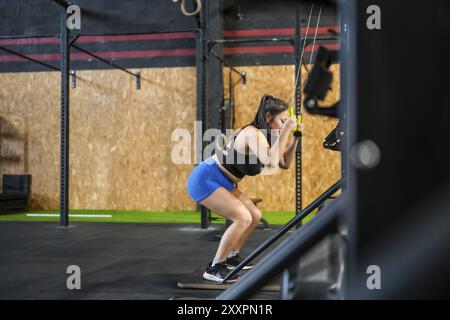 Seitenansicht in voller Länge einer starken asiatischen Frau, die in einem Crosstraining-Fitnessstudio mit Lat Pulldown-Maschine trainiert Stockfoto