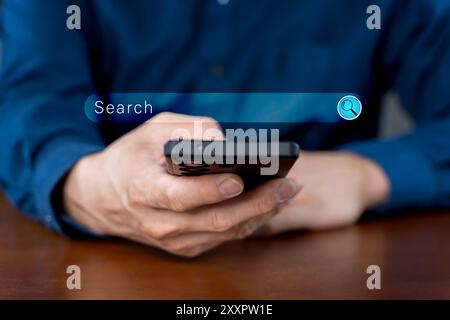 Nahaufnahme der Hand ein Mann, der mit einem Mobiltelefon nach Informationen sucht Interesse auf der Suchmaschinen-Website, während er auf einem blauen Hintergrund steht Stockfoto