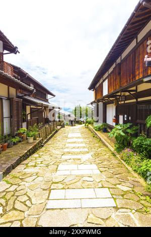 Restaurierte traditionelle Holzhäuser säumen die Seiten eines Steinwanderweges auf dem alten Nakasendo Trail während des Tages in Magome, Kiso Valley, Japan. Stockfoto