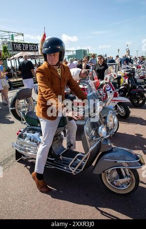 Ein Mod mit brauner Lederjacke sitzt auf einem Roller. Tausende nehmen an dem jährlichen Mod Weekender Teil, der in der englischen Küstenstadt Brighton stattfindet. Dieses Jahr feiert das 60-jährige Jubiläum der Schlacht von Brighton, einer der berühmtesten Schlacht von Brighton zwischen den Mods und Rockers. In den 1950er und 1960er Jahren trafen sich die beiden jungen Subkulturen in südenglischen Badeorten, um Schlachten zwischen sich und der Polizei zu führen. Dies verursachte einen moralischen öffentlichen Aufschrei einer konservativen Nachkriegsgesellschaft, in der die Täter verhaftet, vor Gericht gestellt und inhaftiert wurden. Während die Kipphebelschwelle Stockfoto