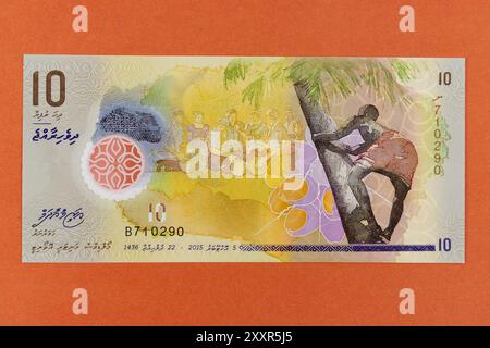 Malediven 10 Rufiyaa gelb-braune Banknote mit Männern und Frauen, die traditionelle Trommeln spielen, und Toddy-Tapper-Porträts Stockfoto