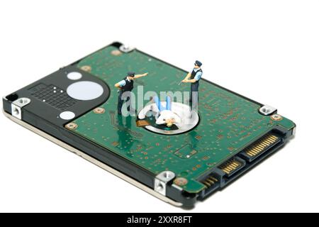 Miniaturmenschen Spielzeug-Fotografie. Eine Gruppe von Polizisten verhaftet Datendiebstahl über der Festplatte. Isoliert auf weißem Hintergrund. Bild Foto Stockfoto