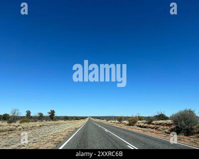 Alice Springs, Australien. August 2024. Eine Straße wenige Kilometer von Alice Springs entfernt führt direkt in entlegene Outback-Regionen. Die Entfernungen in dieser Region sind riesig. Für viele Kinder sind die Entfernungen zu weit, um die Schule zu besuchen. Deshalb bietet die School of the Air Fernunterricht für Kinder im Outback. Die First School of the Air wurde 1951 in Alice Springs eröffnet. Es gibt jetzt 17 Standorte. Vermerk: Carola Frentzen/dpa/Alamy Live News Stockfoto