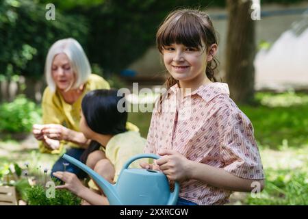 Porträt eines niedlichen Schulmädchens, das sich um Pflanzen im Schulgarten kümmert, während eines nachhaltigen Bildungskurses im Freien. Konzept des Erfahrungslernens und Stockfoto