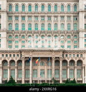 Bukarest, Rumänien, 17. Juli 2024. Modernistische Architektur. Fassade des Parlamentspalastes. Rumänische Flagge. Stockfoto