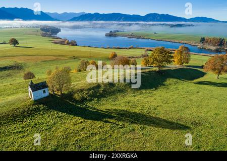 Aus der Vogelperspektive einer kleinen Kapelle an einem See vor den Bergen, Riegsee, Bayern, Deutschland, Europa Stockfoto