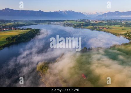 Aus der Vogelperspektive auf einen wunderschönen See mit Nebel im Morgenlicht vor den Bergen, Riegsee, Murnau, Bayern, Deutschland, Europa Stockfoto