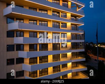 Luftdrohnenaufnahme einer modernen Gebäudefassade, beleuchtet von schlanker LED-Beleuchtung bei Dämmerung, die den Kontrast zwischen der Skyline der Stadt und einfängt Stockfoto