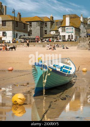 St Ives, Cornwall - an einem warmen Apriltag, bei Ebbe, liegt ein Gig-Boot auf dem goldenen Sand des Hafenstrandes von St Ives in Cornwall, England. Stockfoto