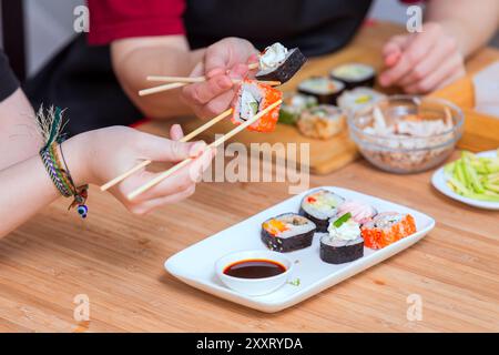 Nahaufnahme von weiblichen Händen, die Stäbchen halten und Sushi-Brötchen essen Stockfoto