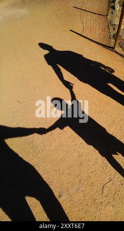 Schatten auf dem Dirt Trail von Eltern, die die Hände des Sohnes halten Stockfoto