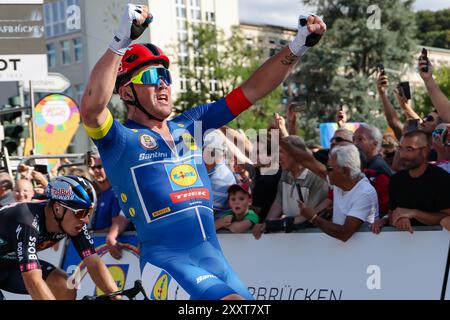 25. August 2024, Saarland, Saarbrücken: Der Däne Mads Pedersen vom Team Lidl-Trek feiert nach dem Sieg der vierten Etappe und dem ersten Gesamtsieg der Deutschland Tour. Foto: Daniel Löb/dpa Stockfoto