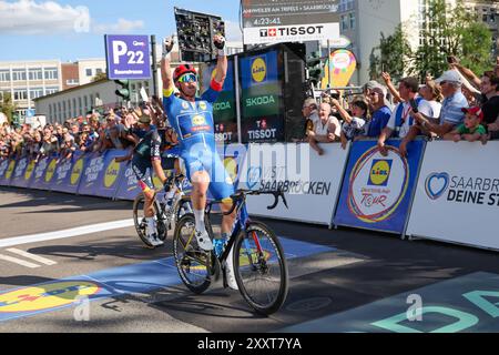 25. August 2024, Saarland, Saarbrücken: Der Däne Mads Pedersen vom Team Lidl-Trek feiert nach dem Sieg der vierten Etappe und dem ersten Gesamtsieg der Deutschland Tour. Foto: Daniel Löb/dpa Stockfoto