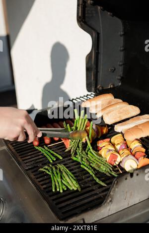 Grillen von Gemüse, Hotdogs und Brötchen auf einem Grill im Freien Stockfoto