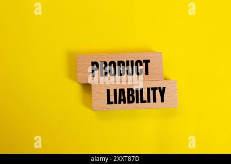 Hinweis zur Produkthaftung auf Holzblöcken mit gelbem Hintergrund. Symbol für konzeptionelle Produkthaftung. Kopierbereich. Stockfoto