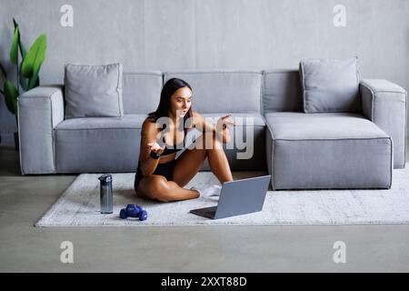 Personal Trainer, der Videoanrufe führt, während er sich auf dem Boden vor dem Laptop auflegt. Stockfoto