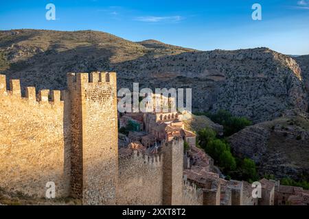 Blick auf die Verteidigungsanlage der mittelalterlichen Mauern von Albarracín, Teruel, Aragon, Spanien, mit goldenem Abendlicht und der Stadt im Hintergrund Stockfoto