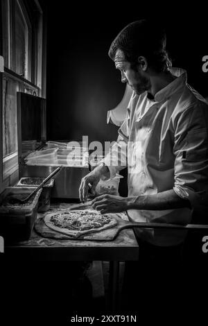 Der Koch bereitet handwerkliche Pizza zu. King's Road Yard Street Market, Pontcanna, Cardiff. Bauernmarkt. Tom's Pizza. Handwerkliches Essen. Schwarzweißbild. Stockfoto