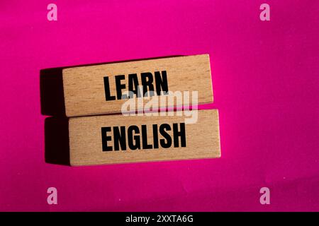 Lernen Sie englische Botschaft auf Holzblöcken mit rosafarbenem Hintergrund. Symbol für konzeptuelles Lernen englisch. Kopierbereich. Stockfoto