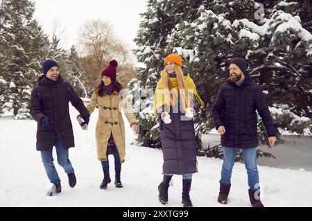 Zwei glückliche junge Paare, die am Wochenende gemeinsam im verschneiten Winterwald spazieren gehen. Stockfoto