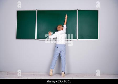 Foto eines charmanten, hübschen, fleißigen Schuljungen, der am 1. september in der Nähe der grünen Tafel im Klassenzimmer antwortet Stockfoto