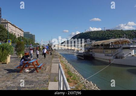 Ungarn, Budapest, die Menschen treffen sich, entspannen und am Ufer der Donau entlang zu spazieren, neben Kreuzfahrtschiffen, die an der Donau ankern, ist die zweitlängste Stockfoto