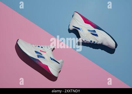 Straßburg, Frankreich - August 2024: Neue Trainingsschuhe Reebok Nano X4. Neuer moderner Trainingsschuh für Damen auf rosa blauem geometrischem Hintergrund. Stilvolle Farbe Stockfoto