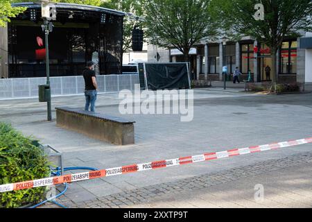 Solingen, Deutschland. August 2024. Absperrband, Polizeischranke auf dem Fronhof, im Hintergrund die leere Bühne gedenken Bundeskanzler Olaf Scholz, Premierminister Hendriok Wuest, Wust, Wirtschaftsministerin Mona Neubaur, Innenminister Herbert Reul und Bürgermeister Tim Kurzbach der drei auf dem Fronhof in Solingen getöteten und verletzten Menschen, vermutlich getötet von einem 26-jährigen Syrer, der als Migrant nach Deutschland kam, Solingen, dpa, 26. August 2024 Stockfoto