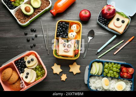 Lunchboxen mit verschiedenen Snacks, eine Flasche Saft und Besteck auf Holztisch, flache Ladefläche Stockfoto