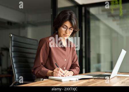 Beschäftigte junge Geschäftsfrau, die im Büro arbeitet und Notizen schreibt. Stockfoto