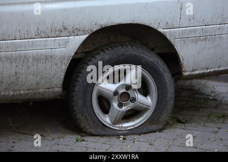 Dreckiges Autorad mit einem Platten Reifen und Anzeichen von Stilllegung. Horizontales Foto. Stockfoto