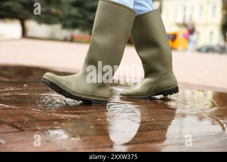 Frau mit Gummistiefeln, die draußen in der Pfütze läuft, Nahaufnahme Stockfoto