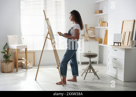 Schöne Frau, die im Studio ein Bild auf Leinwand zeichnet Stockfoto