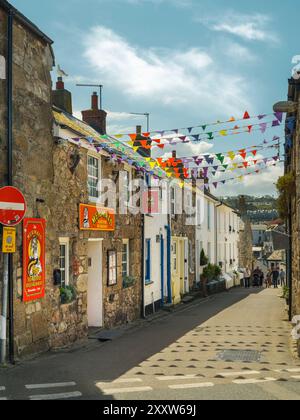 Touristen spazieren durch eine der mit Flecken bedeckten engen Gassen in St Ives, Cornwall, England. Stockfoto