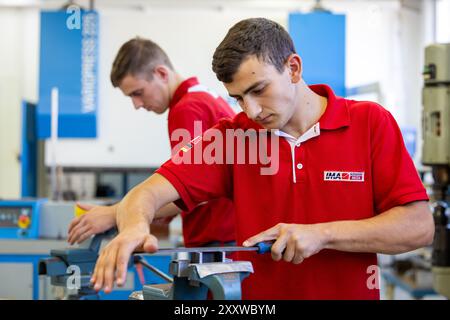 Ranstadt, Deutschland. August 2024. Jonas Adrian (vorne) und Jonathan Seum, Auszubildende Industriemechaniker, üben in der Ausbildungswerkstatt der Hassia Verpackungsmaschinen GmbH. Der Maschinenbauspezialist baut Umformmaschinen, Füll- und Dichtmaschinen und sucht Nachwuchstalente. Quelle: Christian Lademann/dpa/Alamy Live News Stockfoto