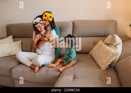 Mutter mit ihren Kindern mit halloween-Masken, die lachend im Sessel sitzen Stockfoto