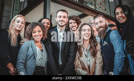 Verschiedene Fachleute lächeln selbstbewusst und posieren gemeinsam in einer modernen Büroumgebung. Das Bild zeigt eine positive und integrative Arbeit Stockfoto