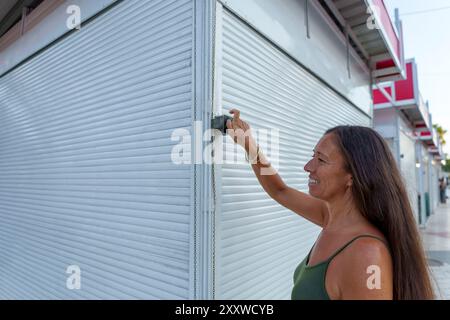 Hispanische Frau in ihren 50ern öffnete ihren Straßenstand, um handgemachten Schmuck aus Aluminiumdraht zu verkaufen Stockfoto