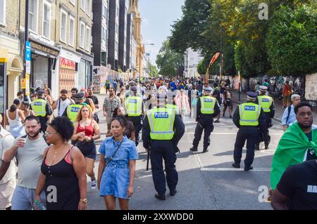 London, Großbritannien. August 2024. Polizeibeamte beobachten die Menschenmassen am zweiten Tag des Notting Hill Karnevals, da die Sicherheit nach Messerstechungen und Festnahmen am Vortag erhöht wird. Quelle: Vuk Valcic/Alamy Live News Stockfoto