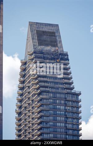 Die Fassadenpflege erfolgt am 100 UN Plaza, einem schwarzen Wohnhochhaus mit Keildach und Balkonen in Midtown East. Stockfoto