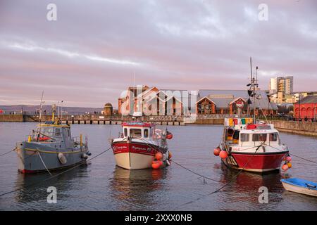 EDINBURGH - 13. JANUAR 2024: Drei Fischerboote im Hafen von Newhaven in Edinburgh während eines malerischen Sonnenuntergangs. Stockfoto