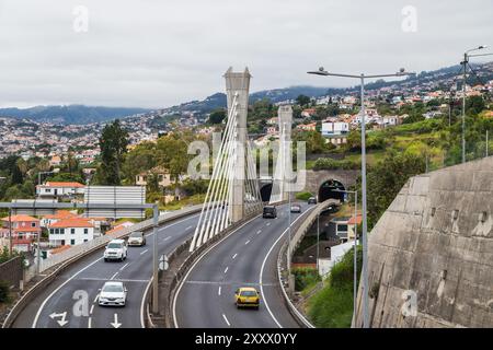 Am 31. Juli 2024 überblickt man eine typische Autobahn um Funchal, Madeira, mit einer zweispurigen Straße, die über eine Brücke und in einen gewundenen Tunnel führt Stockfoto