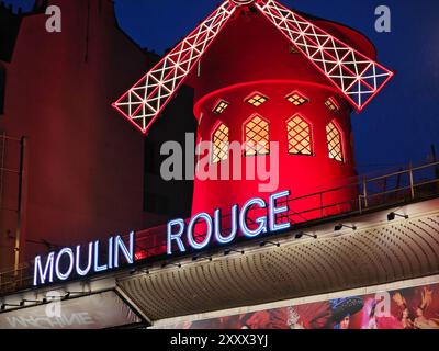 08 26 2024 - Paris, Frankreich. Windmühle Moulin rouge und beleuchtetes Schild an der Fassade bei Nacht. Stockfoto