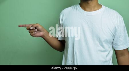 Junger Mann, der mit dem Zeigefinger zur Seite zeigt, während er den Buchstaben G auf der Gebärdensprache zeigt Stockfoto