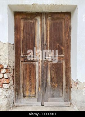 Alte, beschädigte braune Holztür des Ziegelgebäudes Stockfoto