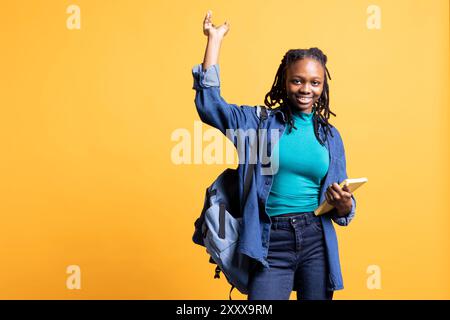 Porträt einer fröhlichen Person mit Buch in den Händen, das auf leeren Kopierraum zeigt, isoliert über dem Studiohintergrund. Fröhlicher Bücherwurm, der Roman hält und den Finger von der Kamera zeigt Stockfoto