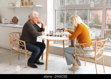 Reifer Mann mit seiner Frau, die Schach am Tisch in der Küche spielt Stockfoto